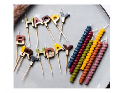 Birthday cake candles in the shape of Happy Birthday letters in various colors with gold details