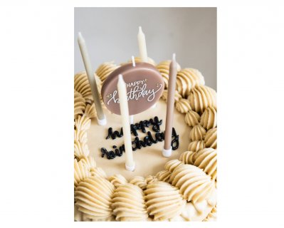 Birthday cake candles in creme, beige and rose color and a round shape candle on a stick with Happy Birthday print
